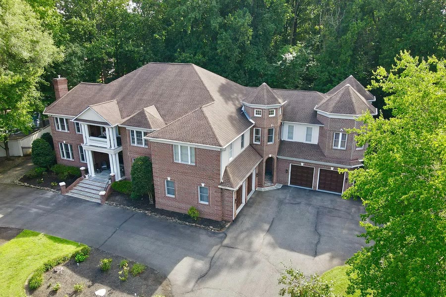 Aerial view of a brick colonial listing and its driveway