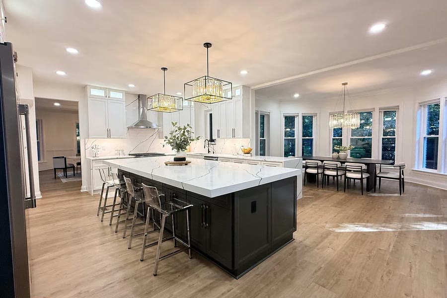 Open white kitchen with a dark island and dining area
